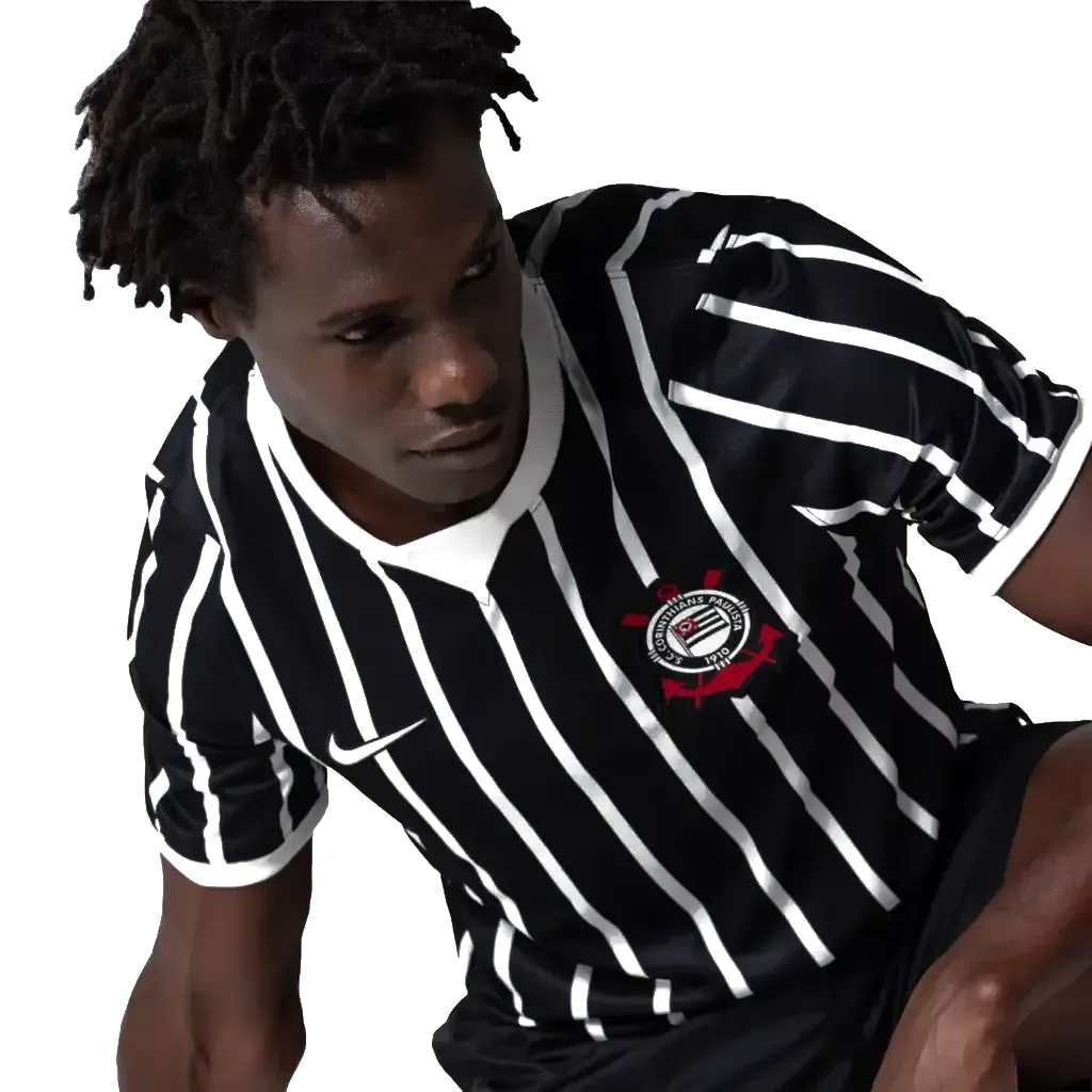 Modelo vestindo a camisa, em close do peito com o escudo bordado.